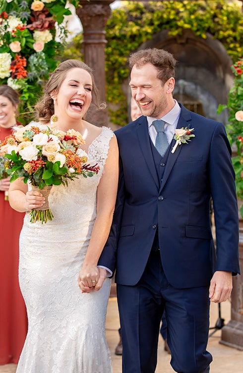 A wedding photo of a bride in a white gown and a groom in a blue suit.