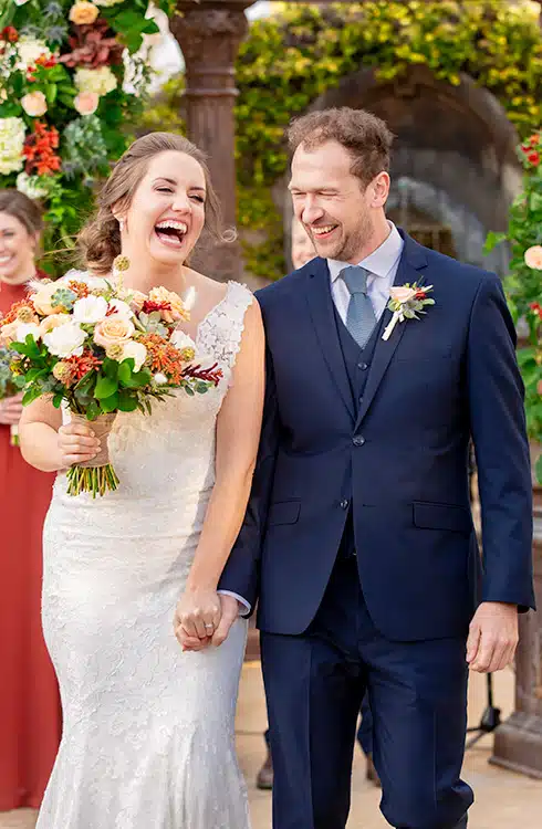 A wedding photo of a bride in a white gown and a groom in a blue suit.