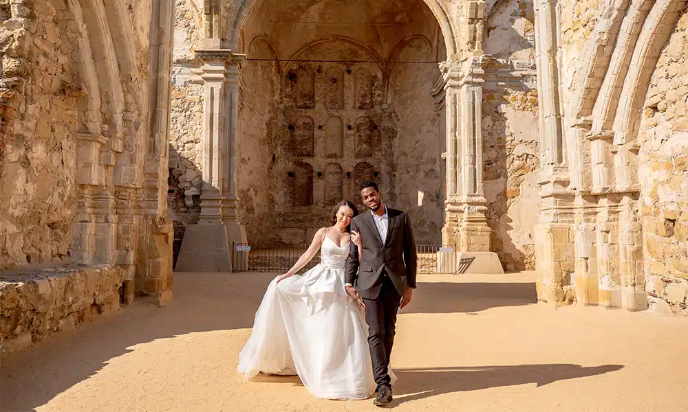 Expert sunlight exposure on bridal gown against stone arches.