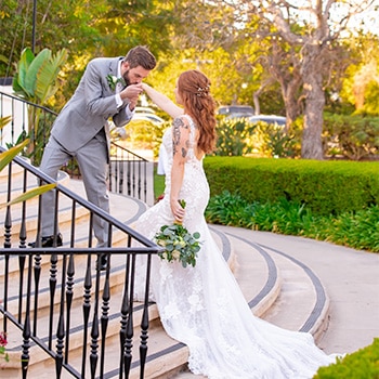 Groom kissing bride's hand in professional wedding portrait.