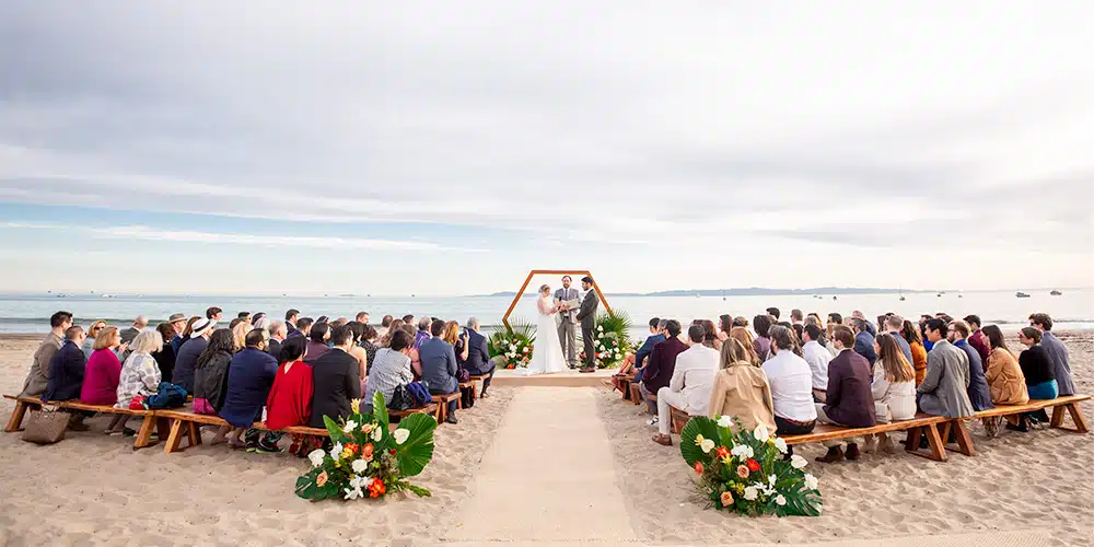 Beach wedding photography: Full view of seaside ceremony.