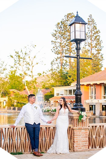 Bride and groom holding hands by lake.