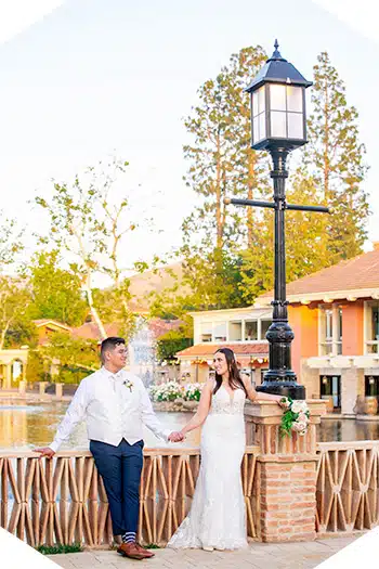 Bride and groom holding hands by lake.