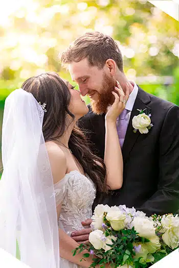 Bride touching groom's face outdoors.