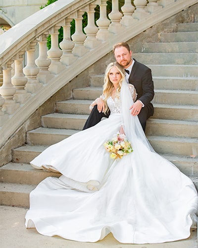 Bride in ballgown with groom on steps.