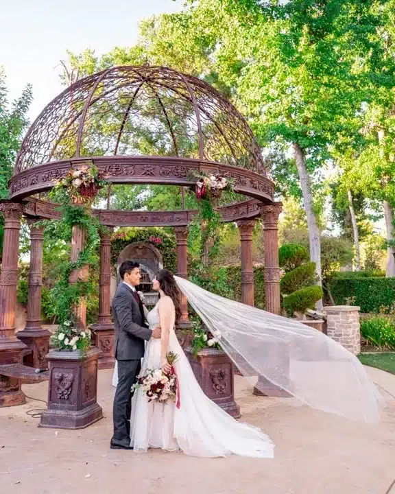 Bride and groom beneath a garden gazebo