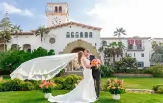 bride and groom kiss in the garden, holding flowers.