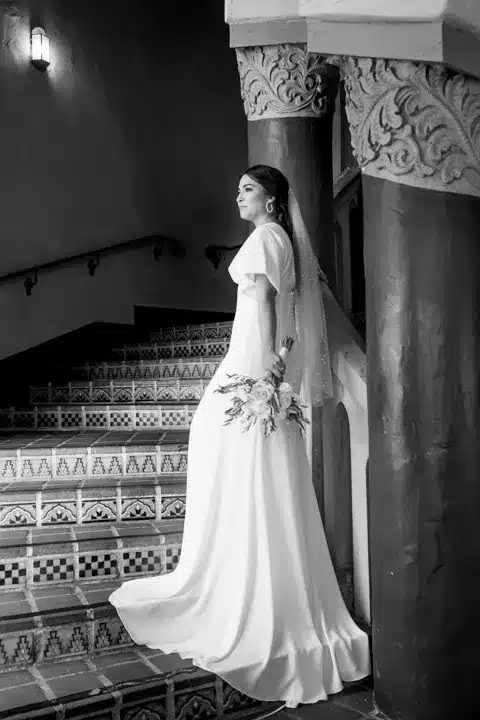 Beautiful bride holding a bouquet, radiating joy indoors.