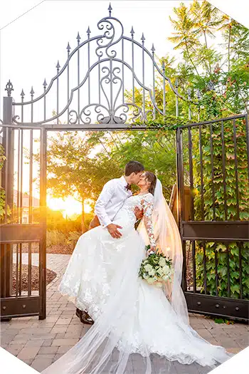 Sunset kiss by ornate garden gates.